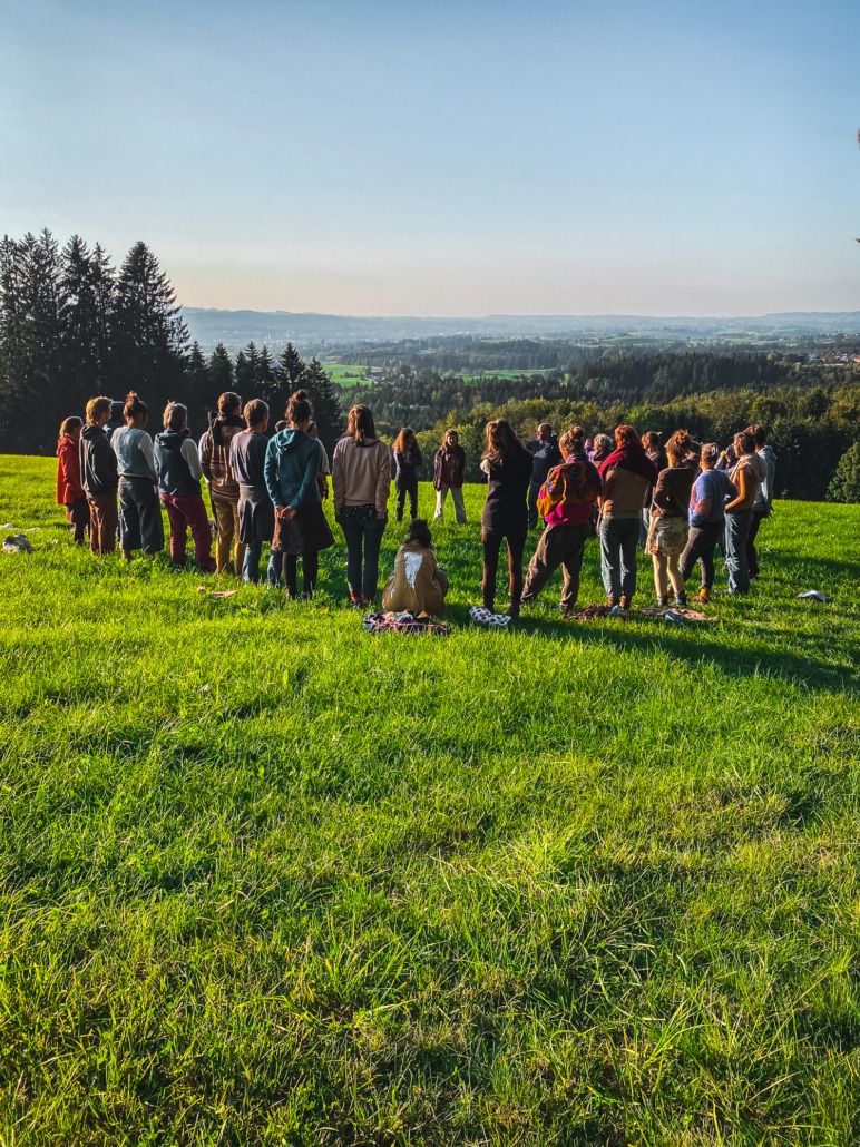Eine Gruppe steht im Kreis auf einer Wiese